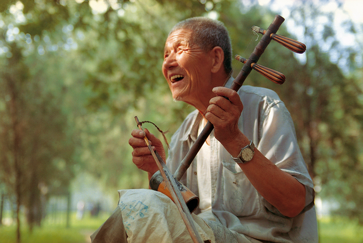 Au matin dans le parc Tiantan, à Pékin, Zhang Yinsheng se détend en jouant de l’<i>er’hu</i>, violon dont l’archet est toujours coincé entre les deux cordes (Chine).