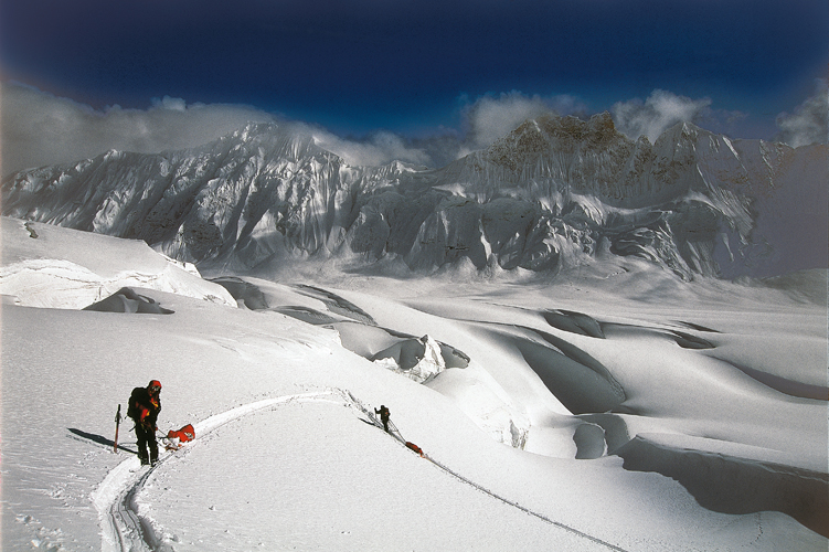 Montée dans la neige profonde, au milieu des crevasses qui défendent l’ultime vallée menant au col d’Hispar (à 5 151 m). Les parois ciselées d’<i>ice flute</i> sont plongées dans une lumière d’altitude ultra-pure.