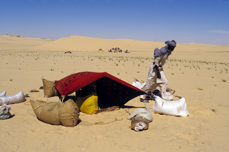 Azan Galemani  caravanier toubou du clan teda  organise un bivouac pour la pause mridienne. Une lourde couverture lance sur des piquets de fortune offre un peu dombre aux voyageurs. Les Toubous sont tous arms, les fusils sont  labri du sable mais  porte de main les femmes portent le poignard de bras, garant de leur honneur.