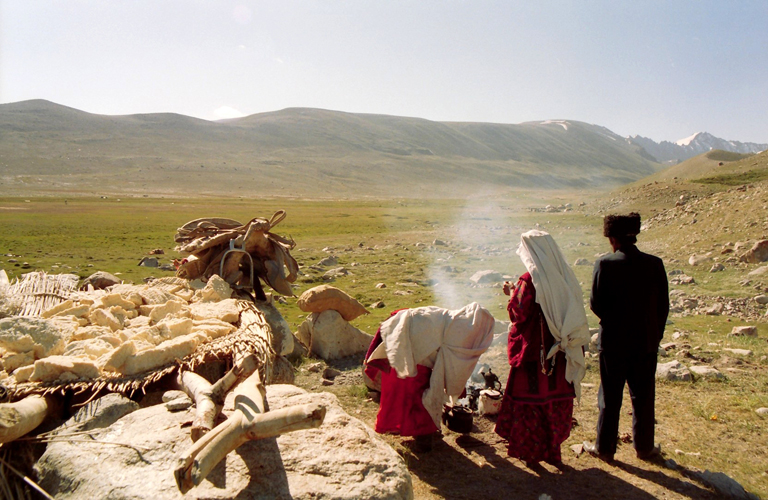 Le chef du hameau dElghonok contemple sa valle, adjacente  celle du Grand Pamir: cest dans cette plaine herbeuse quont lieu  loccasion des ftes  mariages, naissances , des <i>bozkachi</i> qui runissent les meilleurs cavaliers du Pamir.  ses cts, des femmes font bouillir le lait de la traite matinale.